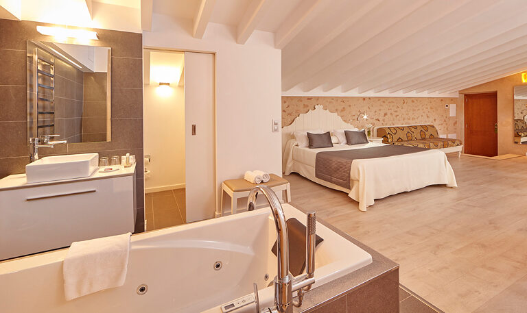 A pair of solid antique pine doors with brass locks, opened onto a suite with a low double bed and twin reading lamps